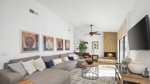 Una sala moderna con un sofá, una mesa redonda de centro, una chimenea y un televisor.