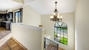 Cozinha espaçosa com eletrodomésticos modernos, uma grande janela com vista para o exterior e um lustre.