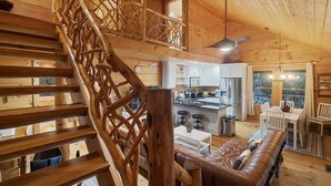 A wooden interior with a staircase, a kitchen area, and a seating area. - Callie's Cabin on the Creek: 3BR w/ Firepit, Dock & Canoe | Pet Friendly (Highlands)