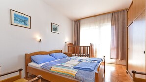 Une chambre à coucher avec un lit en bois, deux tables de chevet, une fenêtre avec des rideaux et deux tableaux encadrés accrochés au mur.