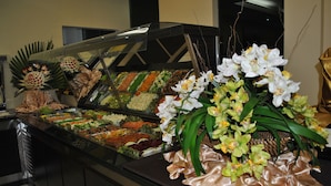 Ein reichhaltiges Buffet mit verschiedenen Speisen und einer dekorativen Orchideen-Anordnung.