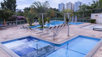 Une piscine dotée de plusieurs couloirs, entourée de chaises longues et de palmiers.