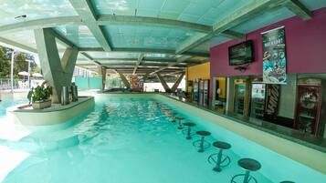 A swimming pool area with a bar and seating along the poolside.
