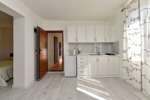 A compact kitchen with white cabinets, a built-in oven, and a coffee maker.