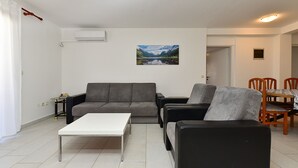 A living room with a sofa, a coffee table, a painting, and a dining area with chairs. - Apartment 85/142 (Istria - Fažana), 50m from the beach (Fažana)