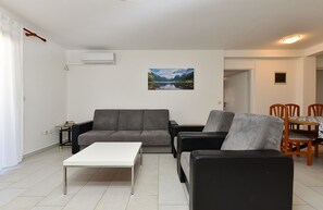 Una sala de estar con sofá, una mesa de centro, un cuadro y un comedor con sillas.