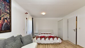 A bedroom with a bed, a sofa, a painting, and a door. - Apartment 85/142 (Istria - Fažana), 50m from the beach (Fažana)