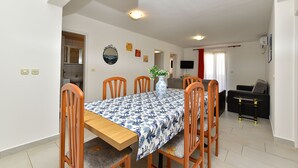 A dining area with a table, chairs, a vase with flowers, and a television on the wall. - Apartment 85/142 (Istria - Fažana), 50m from the beach (Fažana)