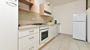 A kitchen with white cabinets, a microwave, a refrigerator, and a dishwasher. - Apartment 85/142 (Istria - Fažana), 50m from the beach (Fažana)