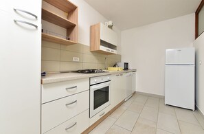 Una cocina con armarios blancos, microondas, refrigerador y lavavajillas.