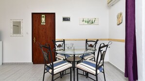Un comedor con una mesa redonda de vidrio, sillas de metal negro y una puerta de madera con un cartel.
