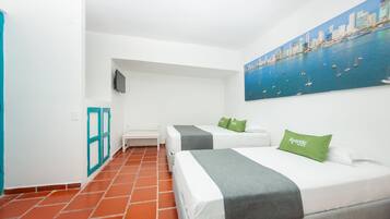 Une chambre d’hôtel avec deux lits, une télévision, un tableau représentant un paysage urbain et un sol carrelé.