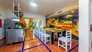 A dining area with a mural of a cityscape, a kitchen with stainless steel appliances, and a tiled floor.