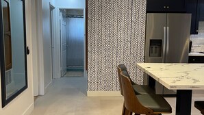 Une cuisine moderne dotée d’un réfrigérateur encastré, d’un coin repas avec une table et des chaises, et d’un ventilateur de plafond.