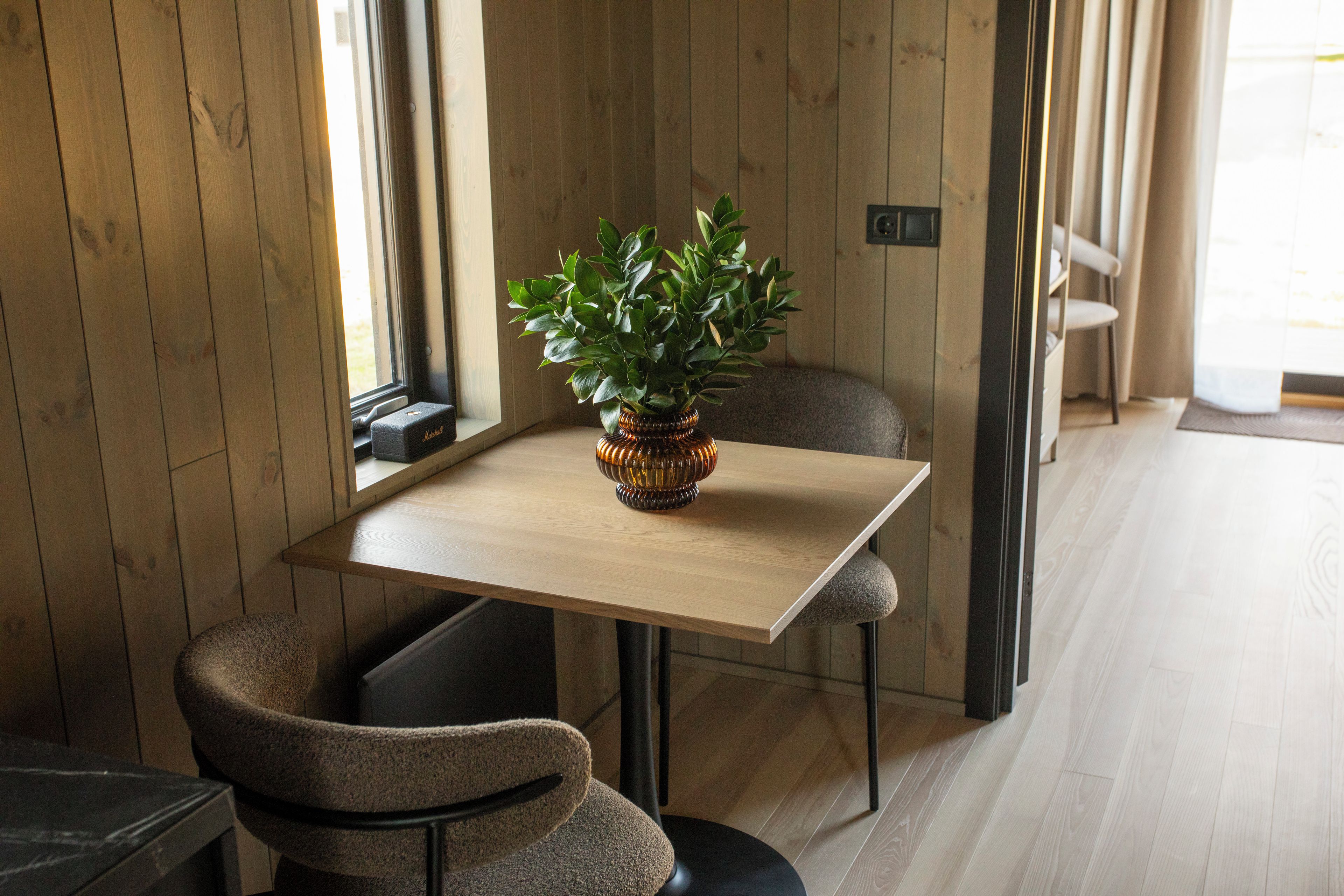 A room with a wooden table, a potted plant, and a chair.