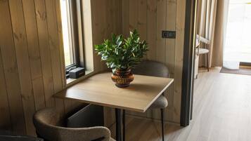 A room with a wooden table, a potted plant, and a chair.