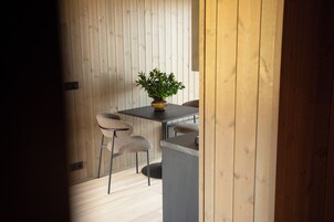 Una habitación con pared de madera, una mesa con sillas y una planta en maceta.