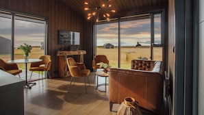 A modern interior with wooden walls, large windows, and a cozy seating area with leather chairs and a sofa. - Seljalandsfoss Horizons (Rangárþing eystra)