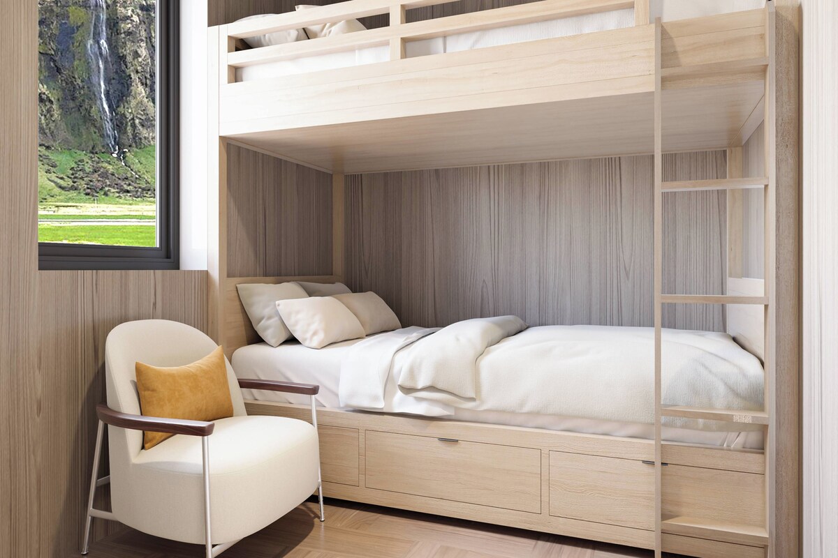 A bunk bed room with a view of a waterfall, a chair with a cushion, and a wooden floor.