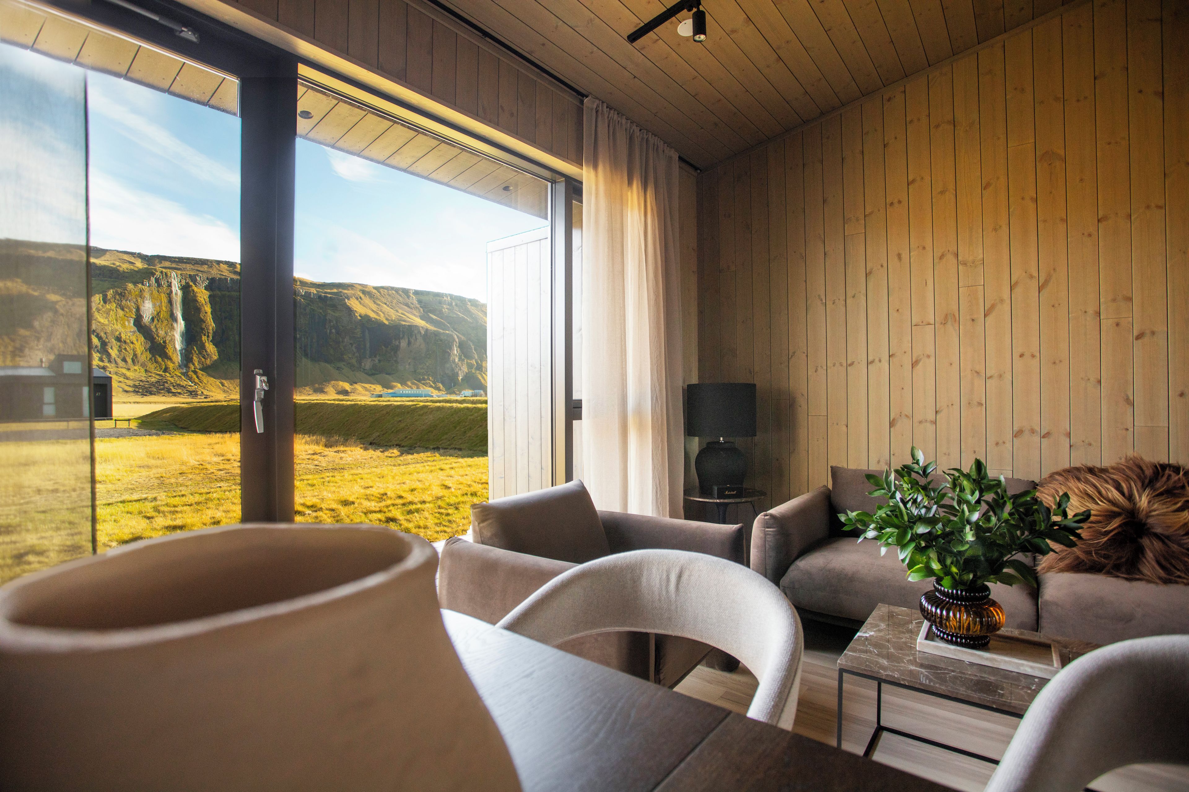A modern interior with a large window, wooden walls, and a view of a mountainous landscape.