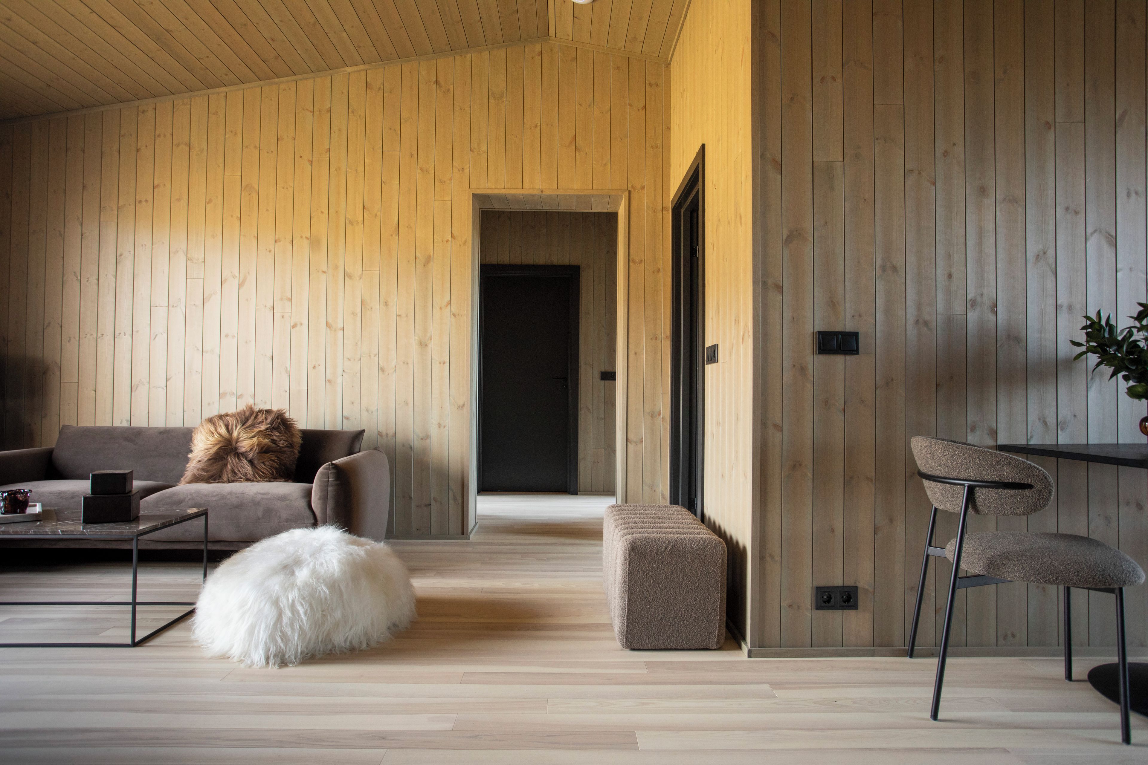 A modern living room with a wooden floor, a sofa, a coffee table, and a chair.