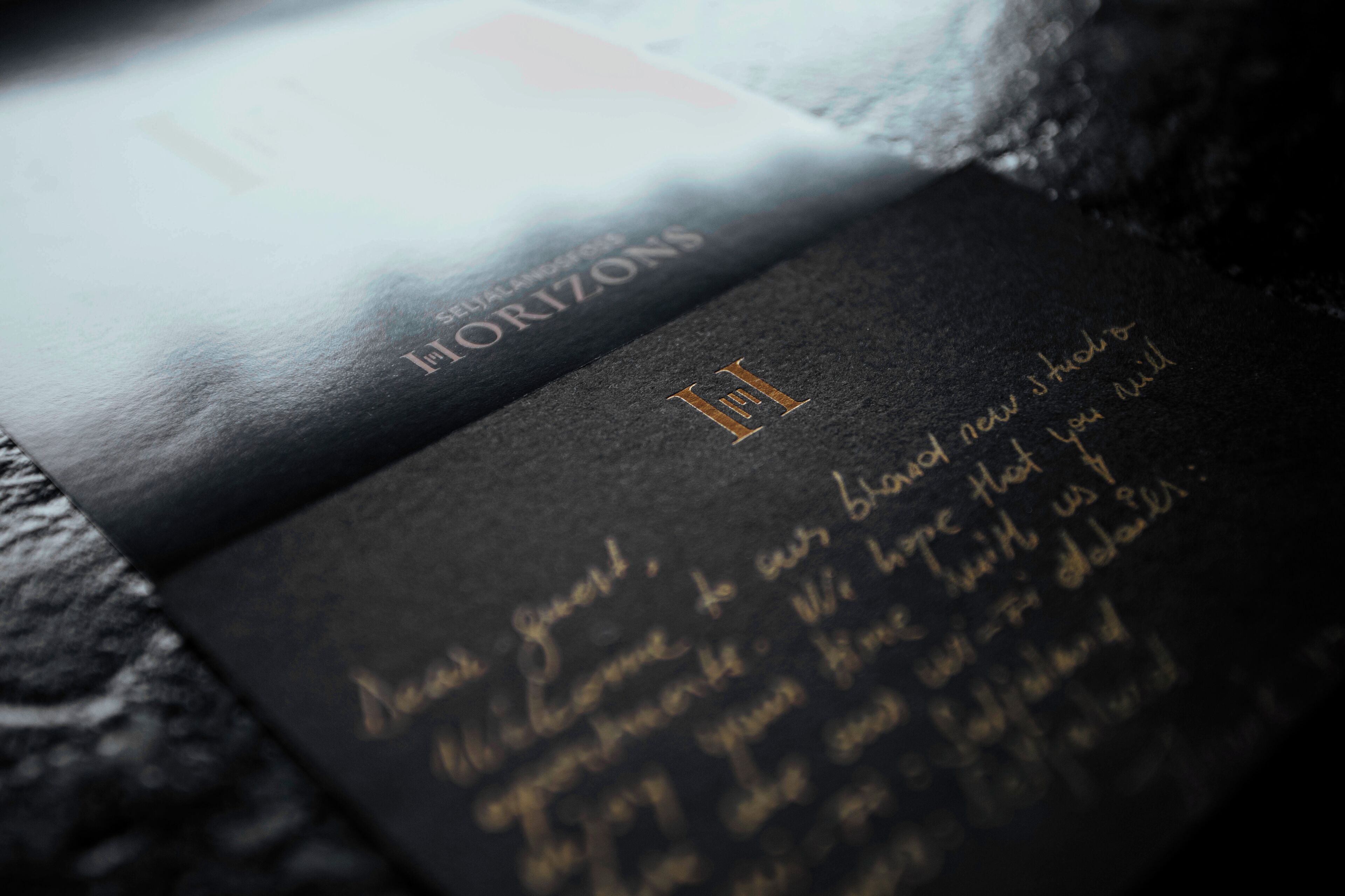 Un gros plan d’un livret noir orné de lettres dorées et d’un logo, posé sur une surface texturée.