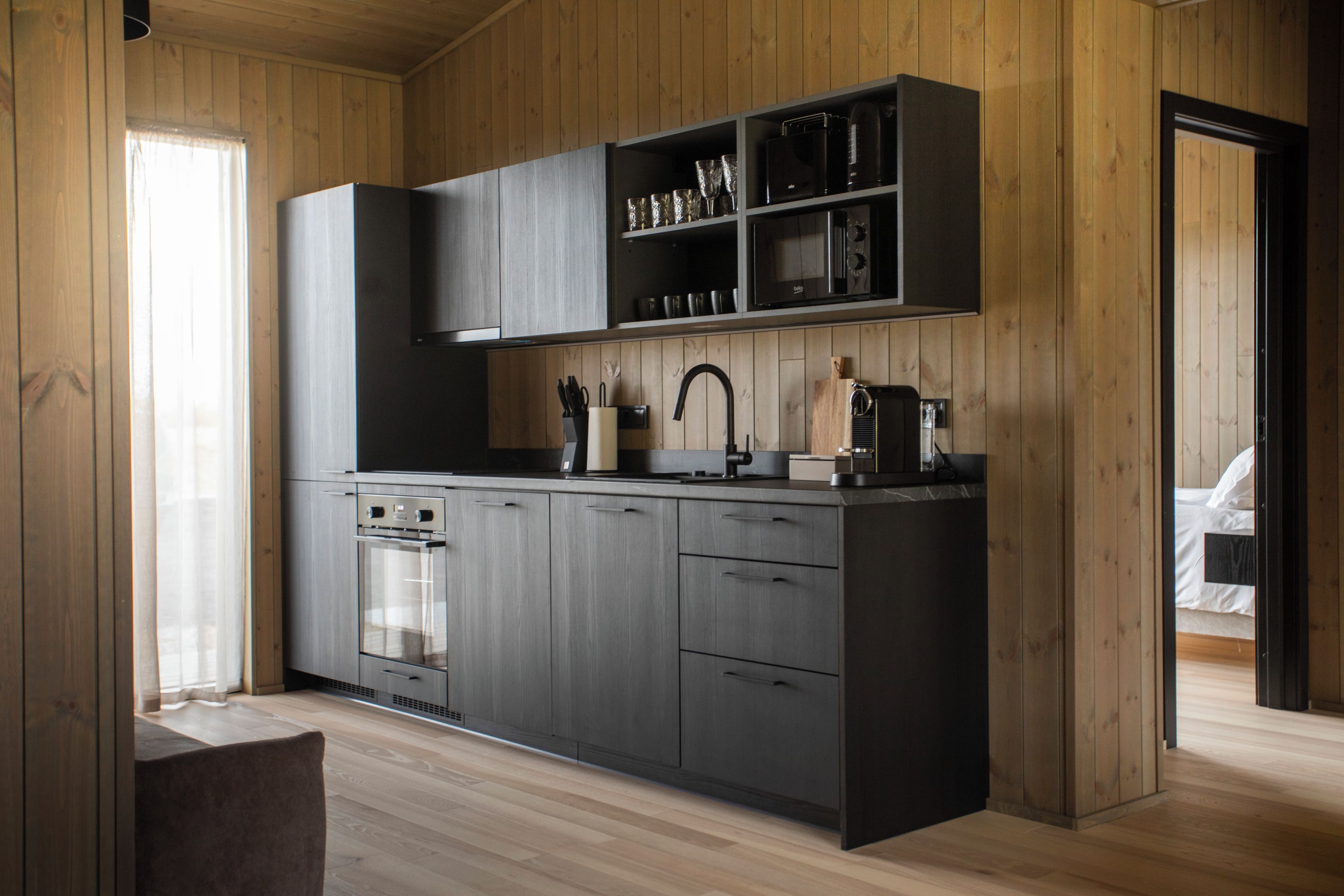 Une cuisine moderne avec des meubles en bois, un four encastré et un plan de travail agrémenté de divers ustensiles de cuisine.