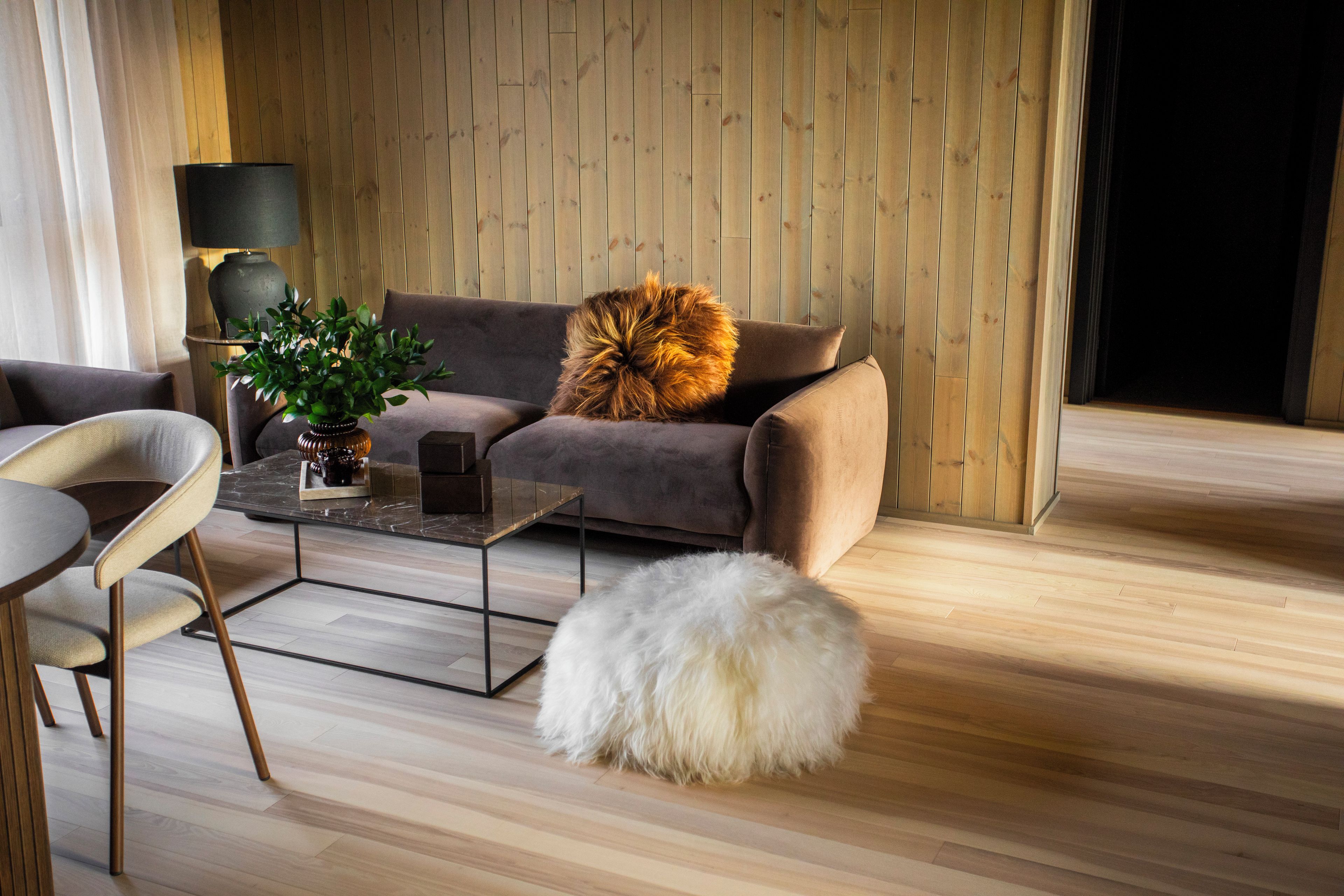 A modern living room with a sofa, a coffee table, a chair, a lamp, and a plant.