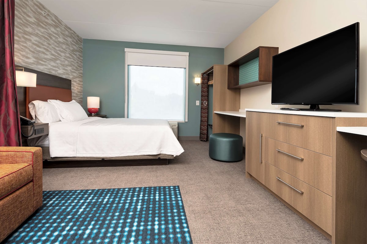 Une chambre d’hôtel avec un lit, une télévision, un bureau et une chaise.