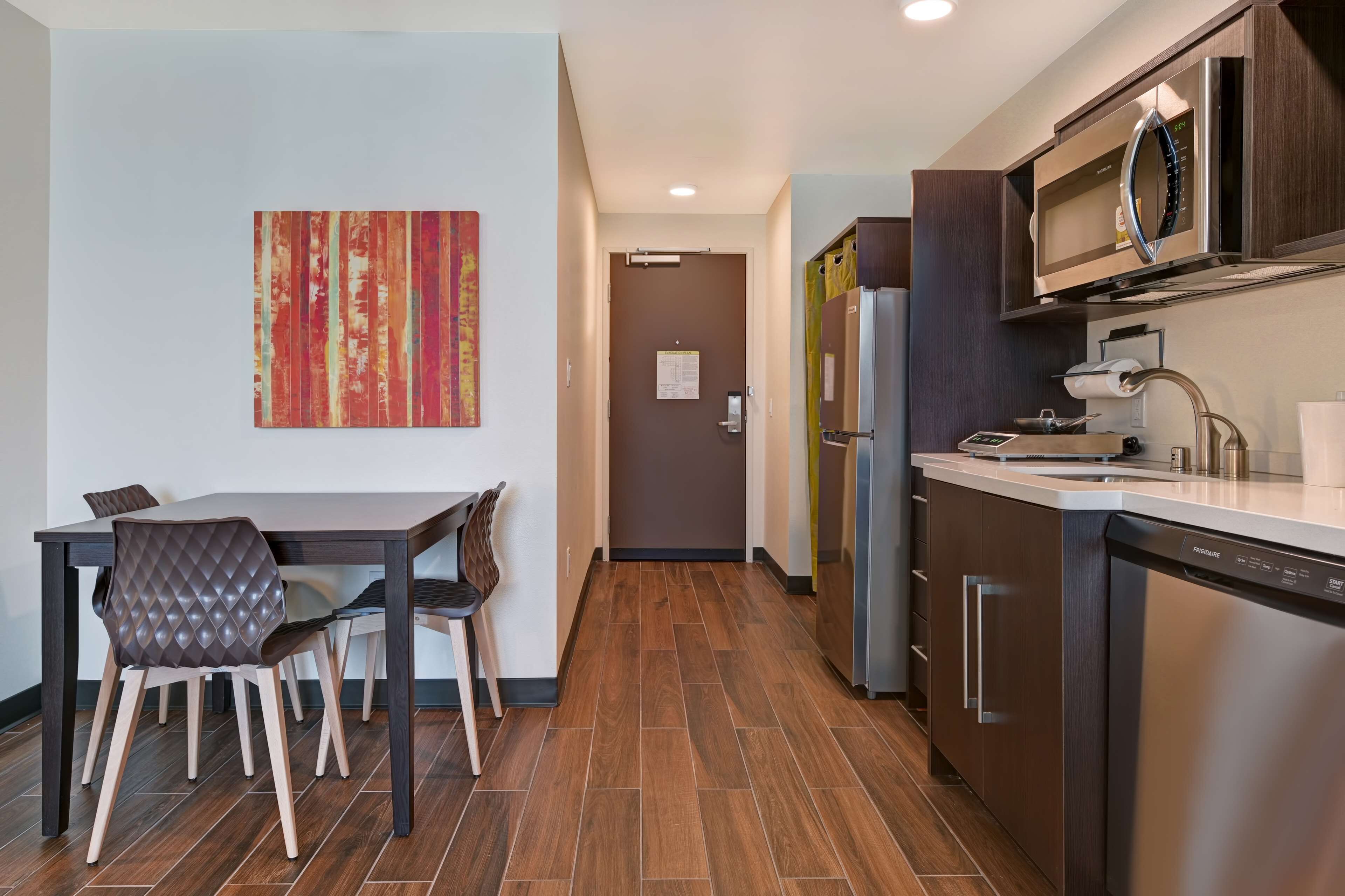 A modern kitchen with a dining area, featuring a stainless steel refrigerator, microwave, and dishwasher.