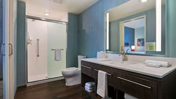 Une salle de bain moderne avec une douche à parois de verre, des toilettes blanches et un meuble-lavabo doté d’un grand miroir.