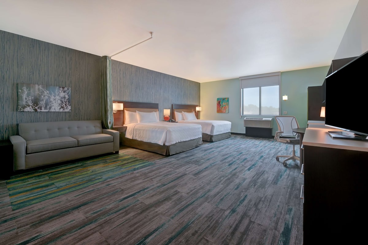 Een hotelkamer met een bank, twee bedden, een bureau en een televisie.