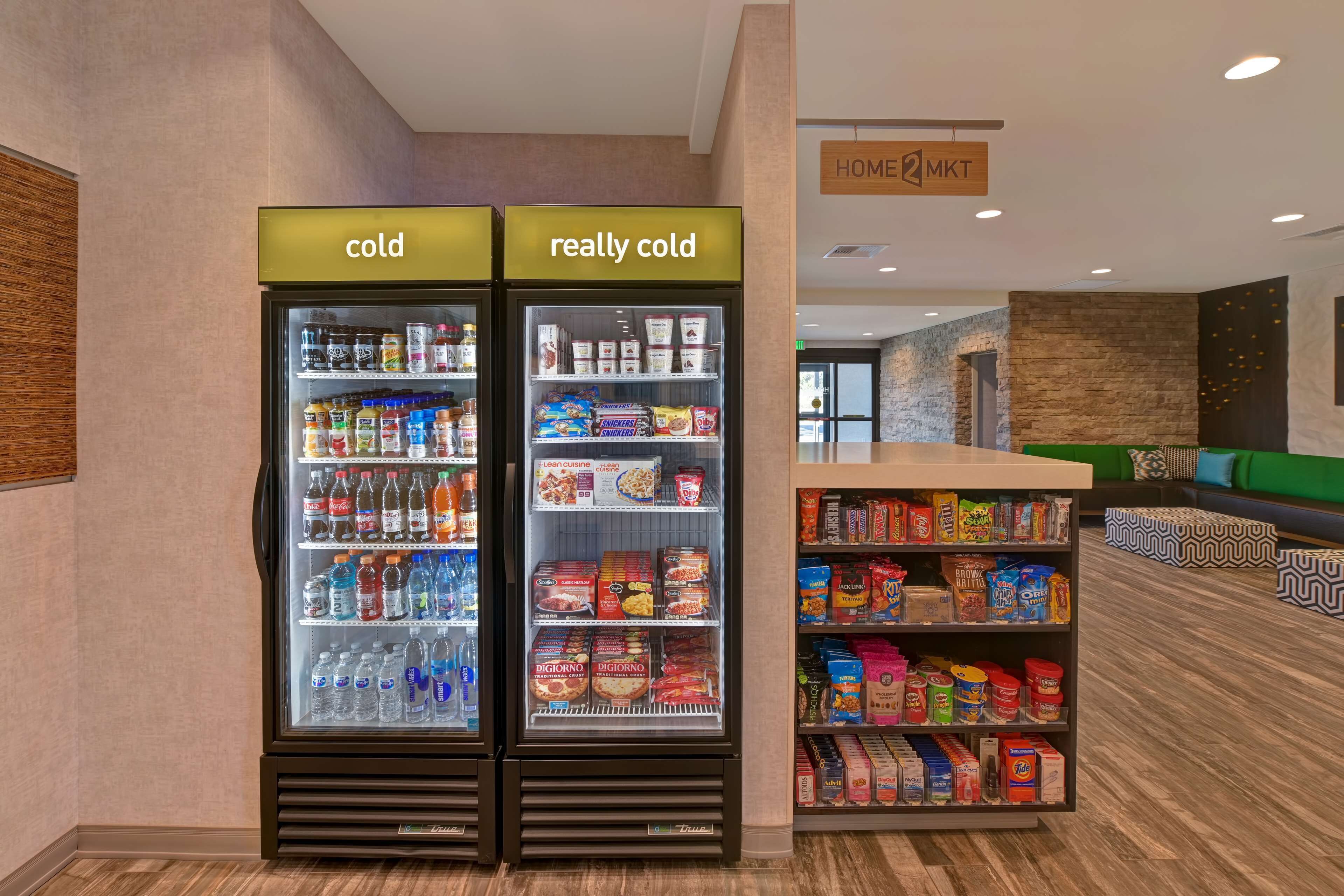 A hotel lobby with two refrigerated display cases labeled "cold" and "really cold," and a shelf stocked with snacks and beverages.
