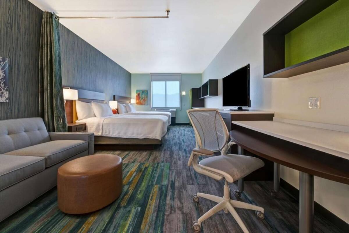 Een hotelkamer met een bed, een bank, een bureau, een stoel en een televisie.