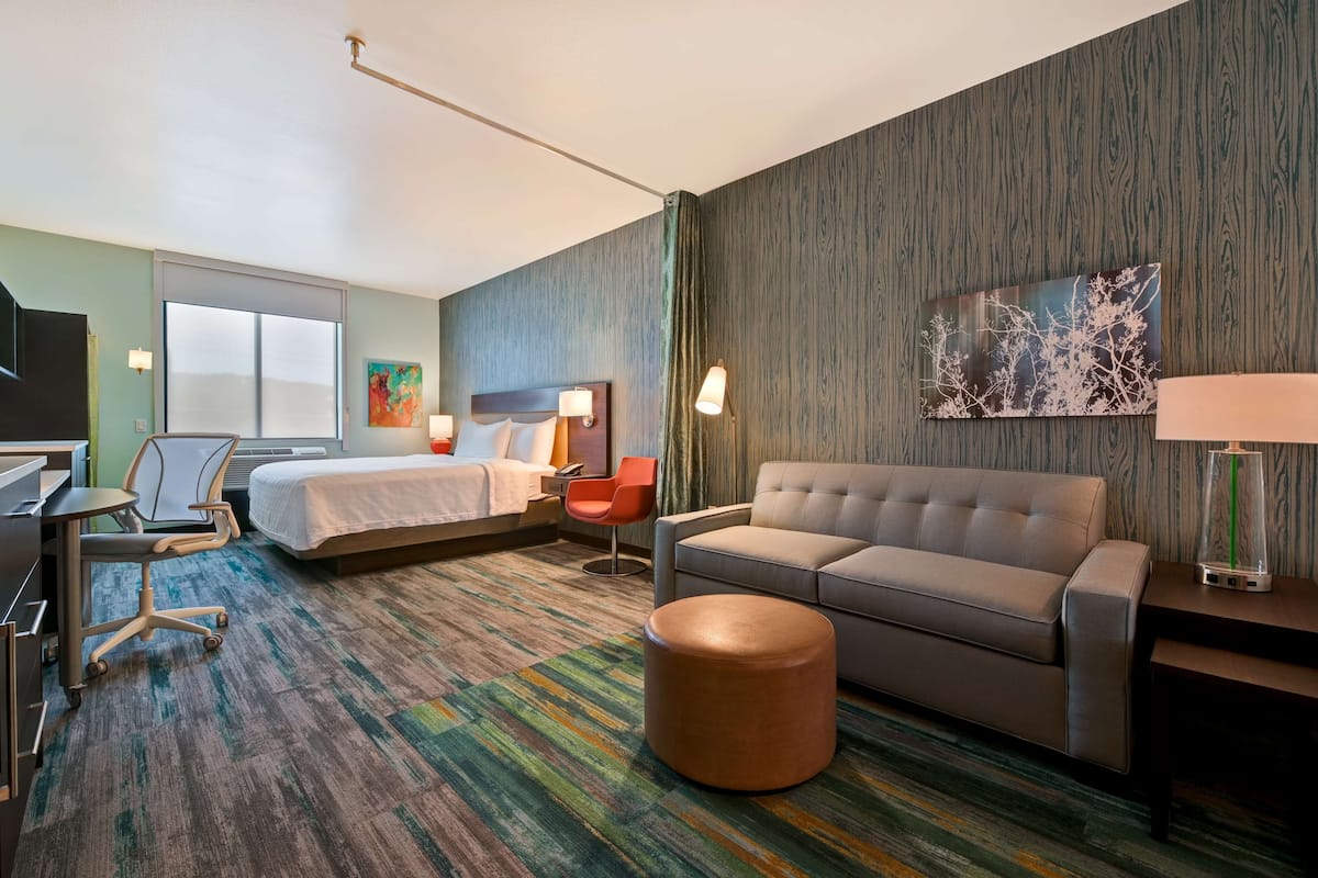 Een hotelkamer met een bed, een bank, een bureau en een stoel.