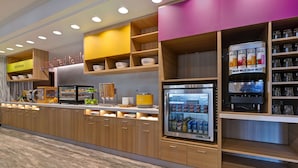 A modern kitchen area with wooden cabinets, a built-in coffee machine, and a beverage dispenser.