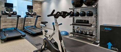 Une salle de sport équipée de tapis de course, d’un vélo d’appartement et de divers appareils d’exercice.