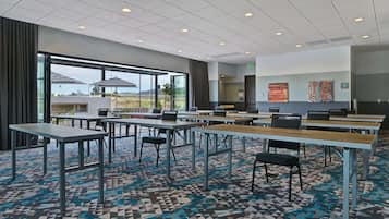 A conference room with tables and chairs, large windows, and a patterned carpet.