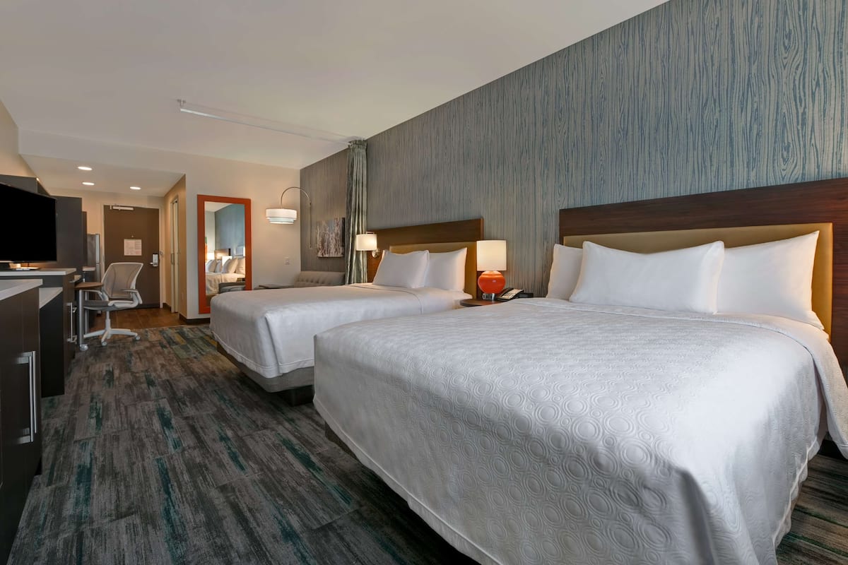 Een hotelkamer met twee bedden, een bureau, een stoel en een televisie.