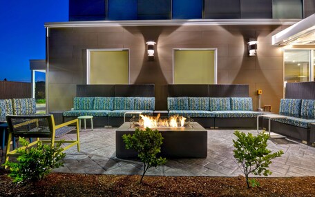 An outdoor seating area with a fire feature, sofas, and chairs.