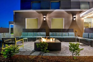 Un área de estar al aire libre con una chimenea, sofás y sillones.