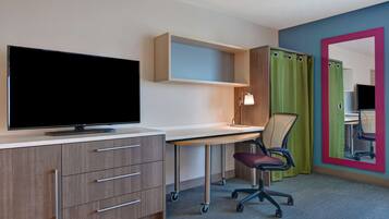 Un dormitorio moderno con televisión, escritorio, silla y un espejo grande.