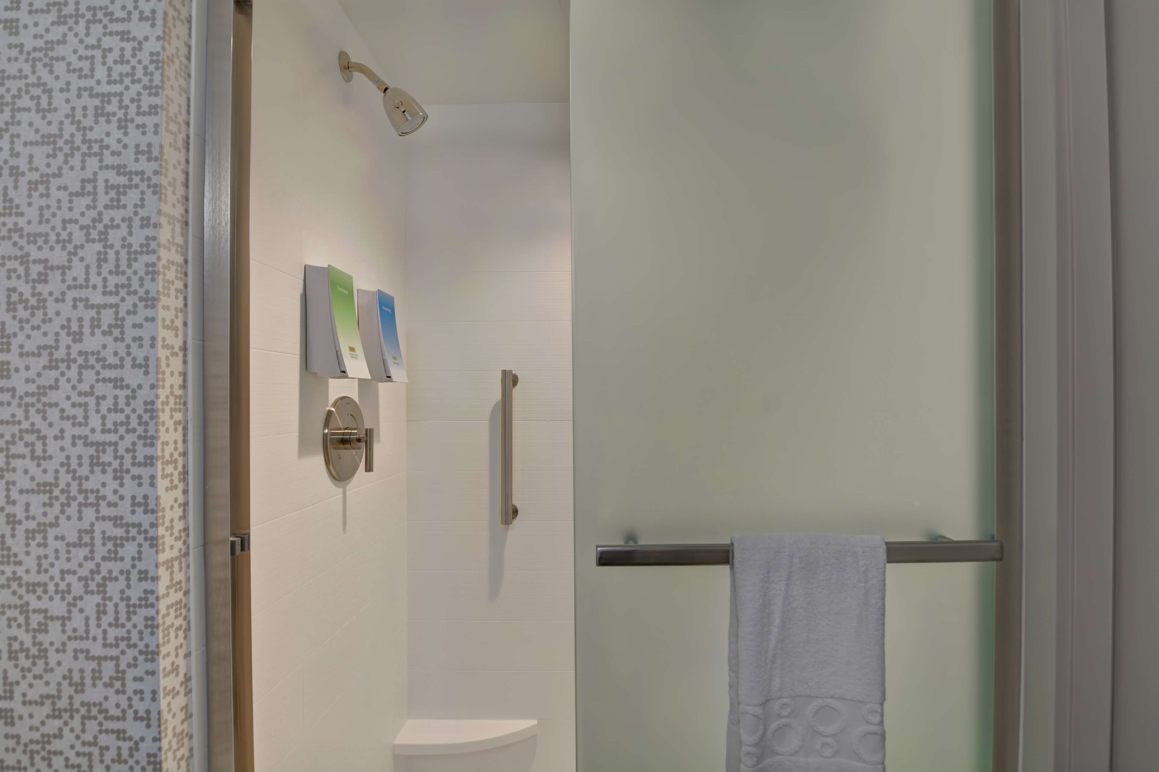 Un baño moderno con cabina de ducha de vidrio, inodoro y toallero.