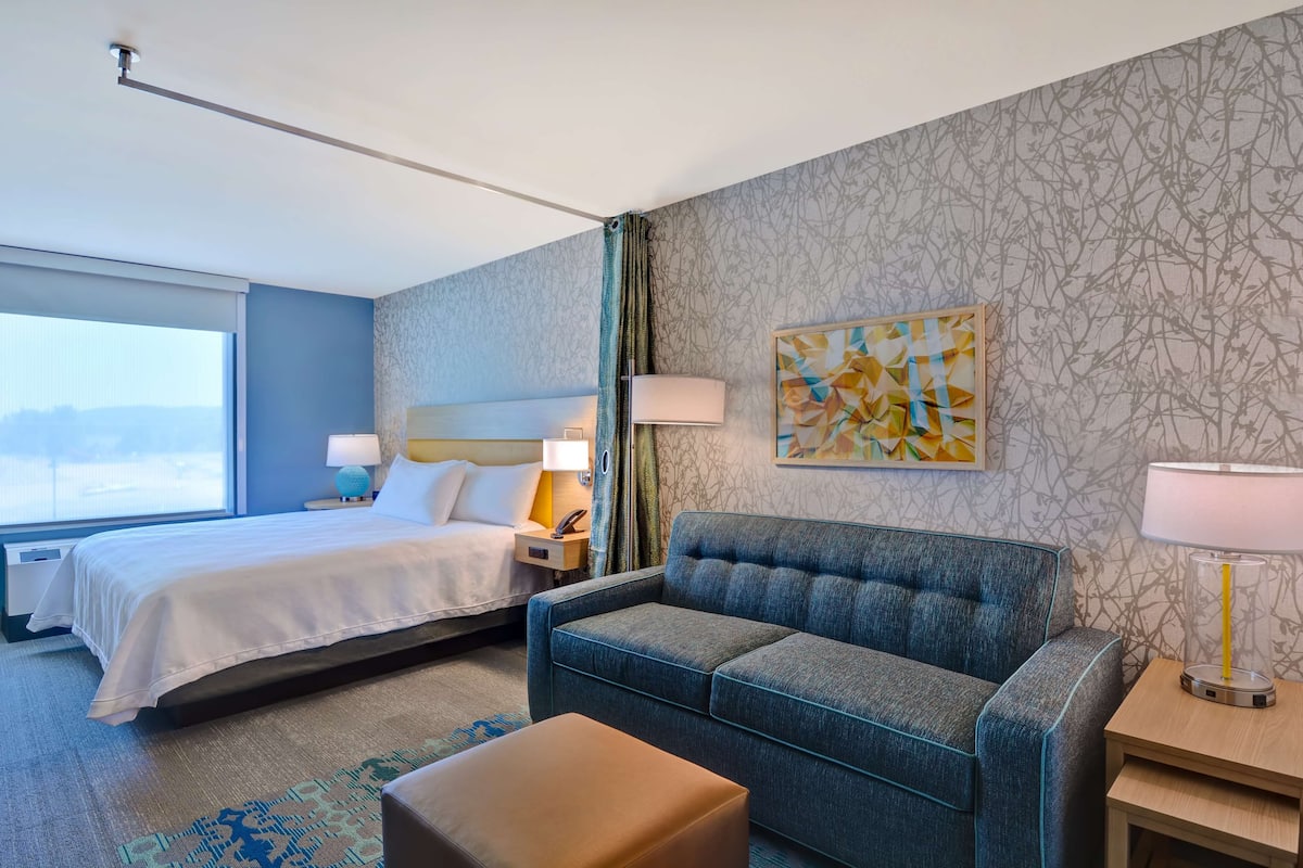Ein Hotelzimmer mit Bett, Sofa, kleinem Tisch und Lampe.