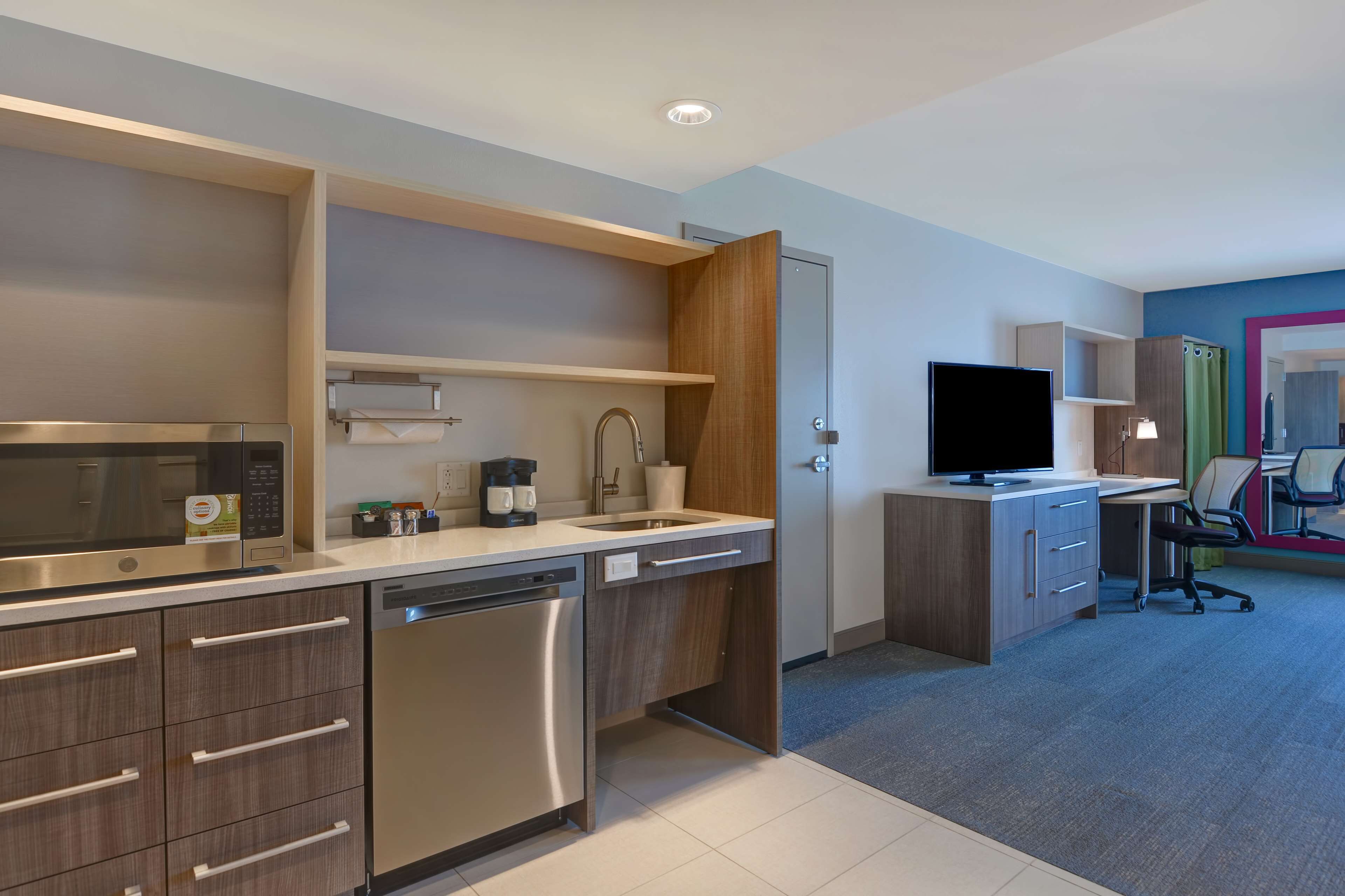 A modern kitchen with built-in appliances, a dishwasher, and a countertop with a coffee maker.