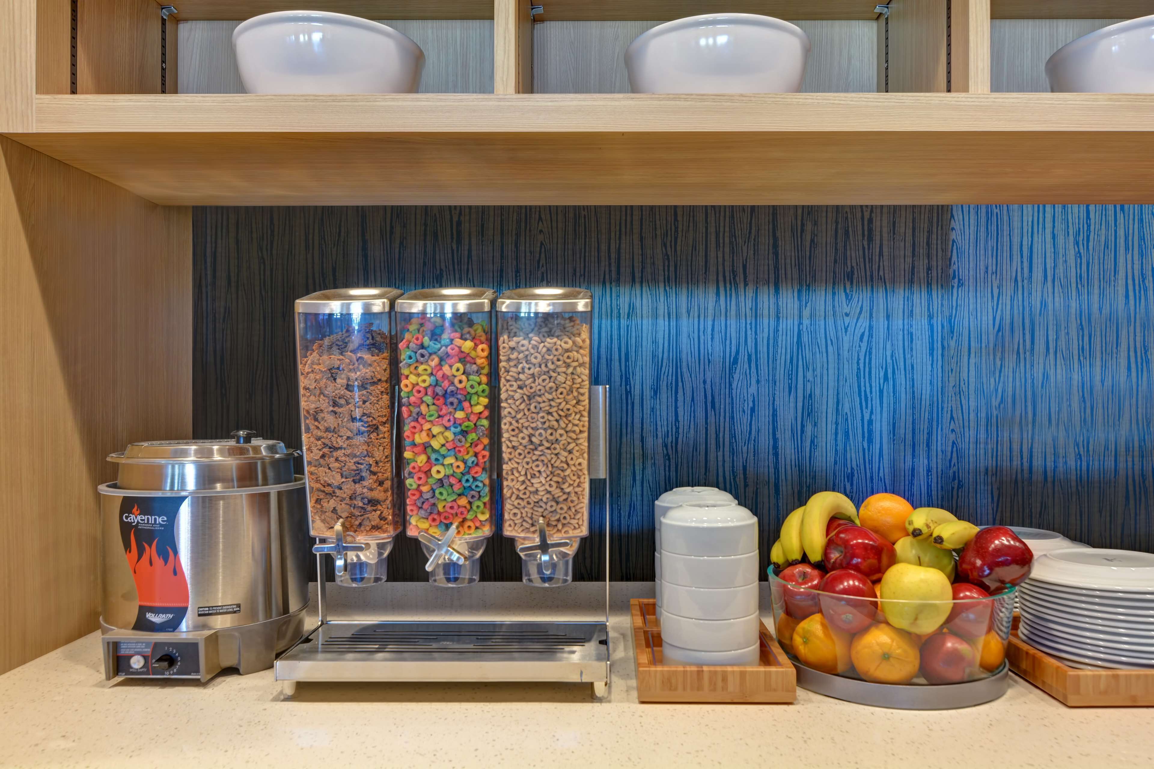 A breakfast bar with a coffee machine, cereal dispensers, and a fruit bowl.