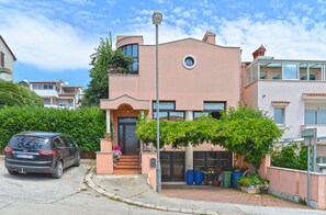 Une maison moderne à deux étages, dotée d’une façade incurvée, de grandes fenêtres et d’une petite fenêtre circulaire au deuxième étage.