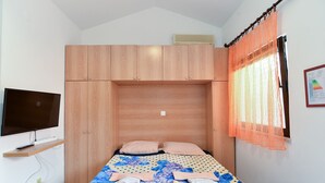Een slaapkamer met een bed, een televisie en een raam met gordijnen.