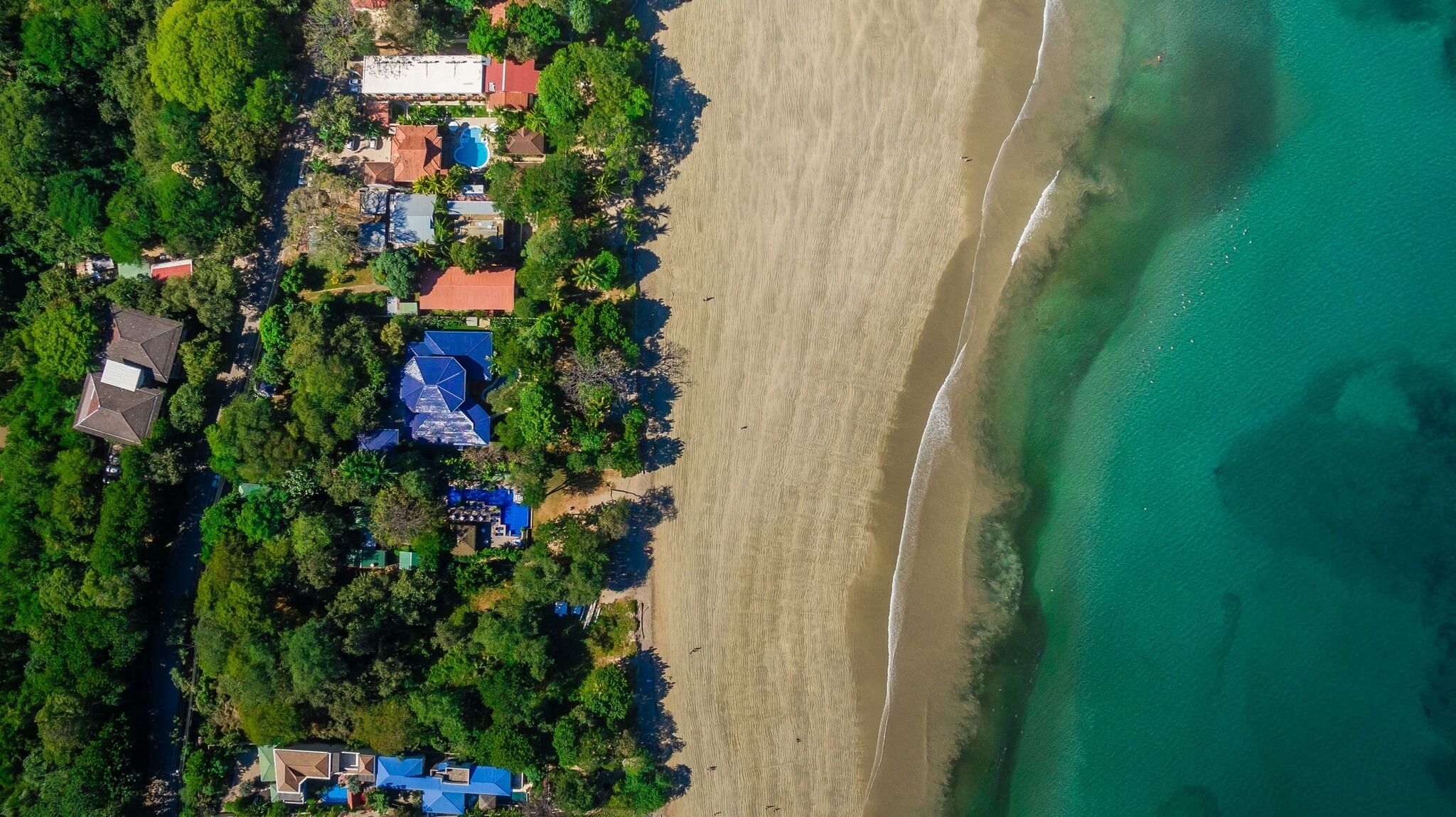 Vista aérea de una propiedad costera con varias edificaciones, una playa y una vista despejada del océano.