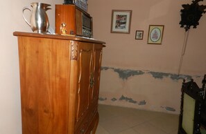 Cozy room with a wooden cabinet, radio, and framed pictures adorns the walls.